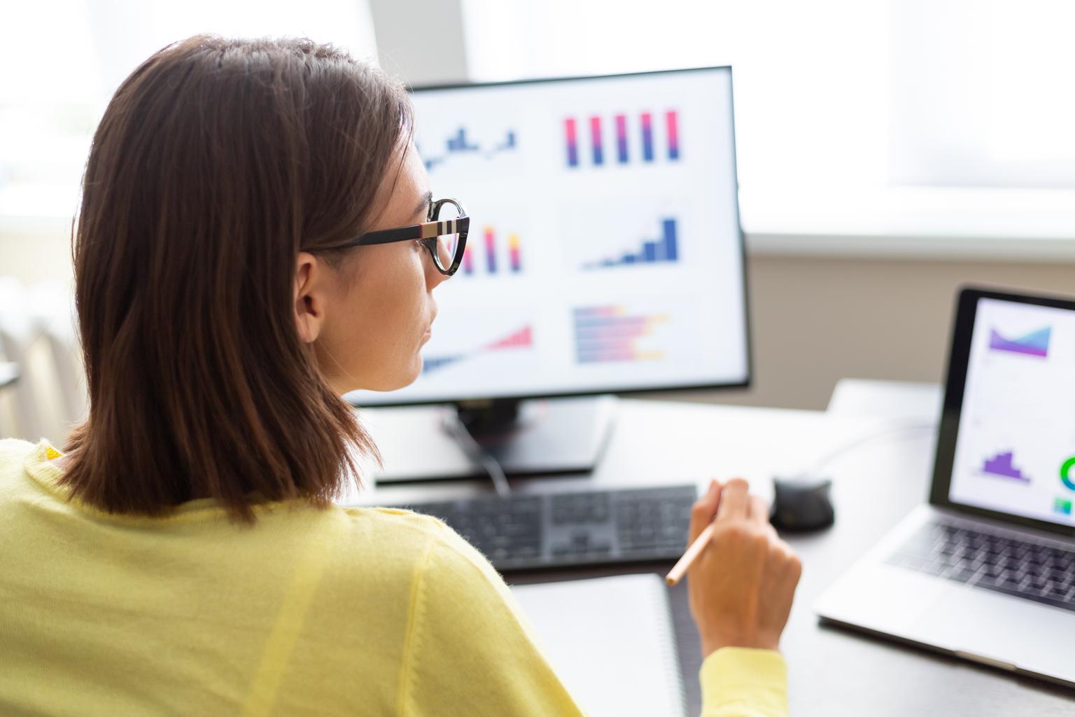 A female financial advisor analyzes data on a dashboard with graphs