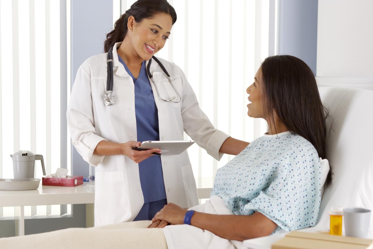 Female doctor talking to female patient in a ward room