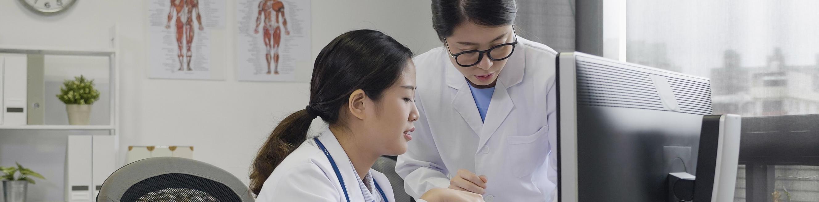 Asian female doctors having a discussion using a tablet and computer in a clinic 