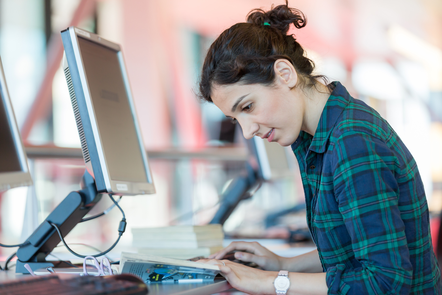 Student sitting at computer desk in public building, studying