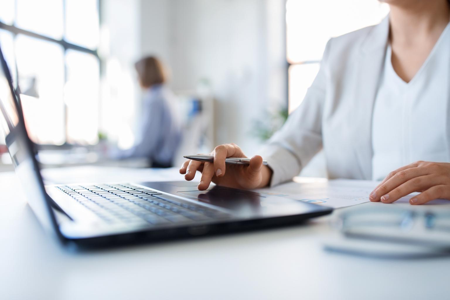 Portrait of businesswoman with laptop and papers working at office