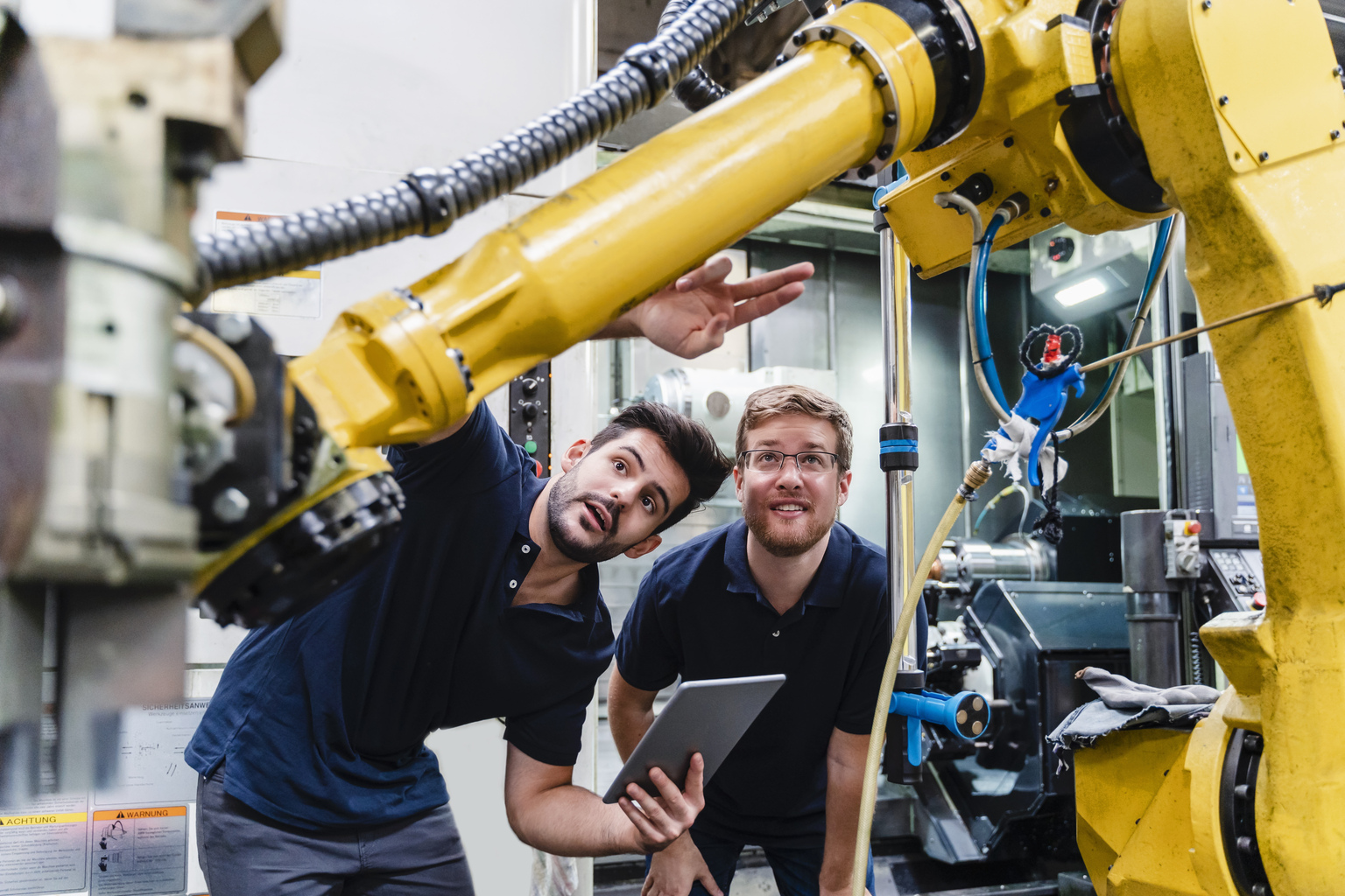 Colleagues examining machines at manufacture industry