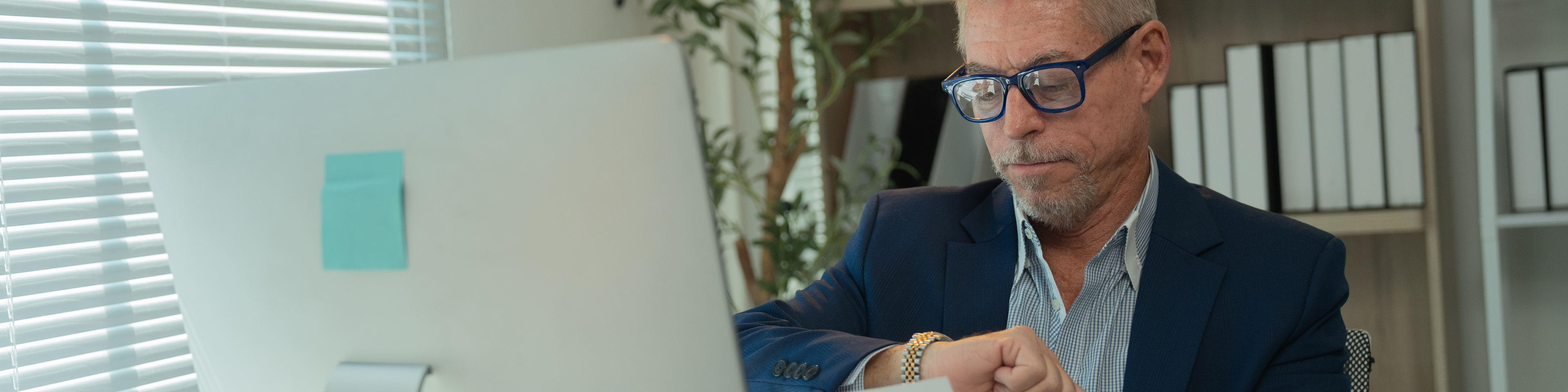 Man looking at his watch while reviewing a document