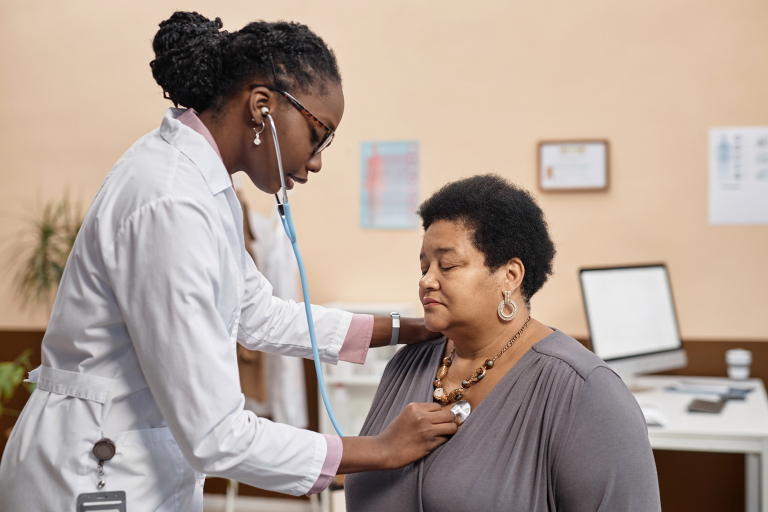 Female health practitioner conducting a medical examination on a female patient using a stethoscope