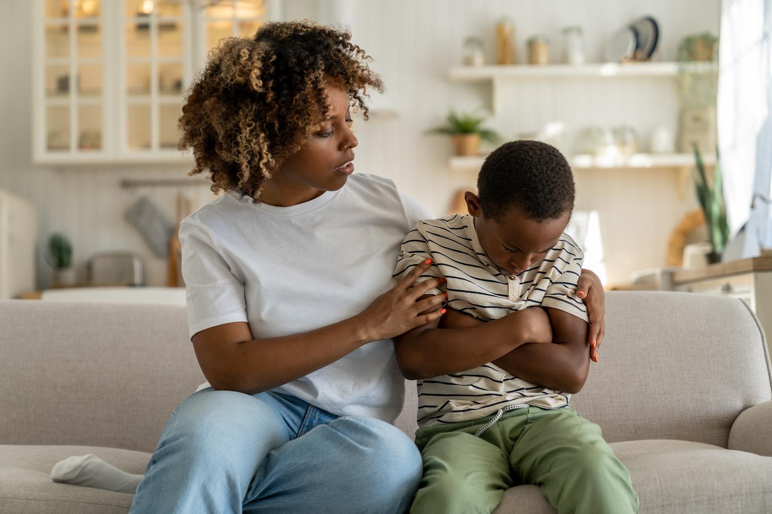 African american mother calms her child while sitting on couch