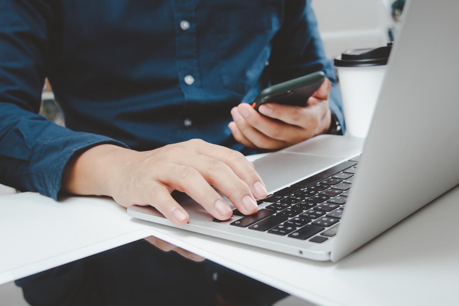 Man uses mobile phone and computer