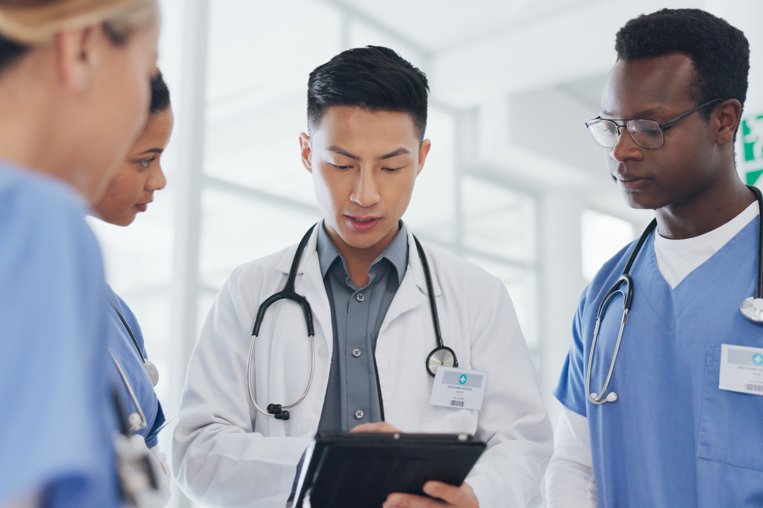 Asian male doctor using tablet in meeting with nurses for surgery planning or treatment in hospital setting