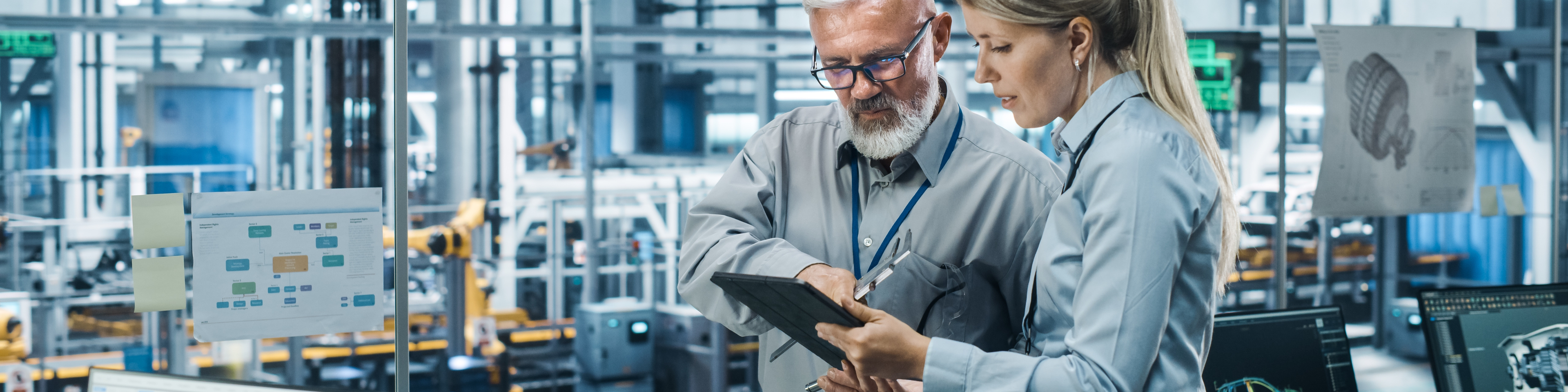 Car Factory Office: Manager Talks with Senior Engineer, Use Tablet Computer to Design Production Conveyor for Advanced Power Engines. Automated Robot Arm Assembly Line Manufacturing Vehicles