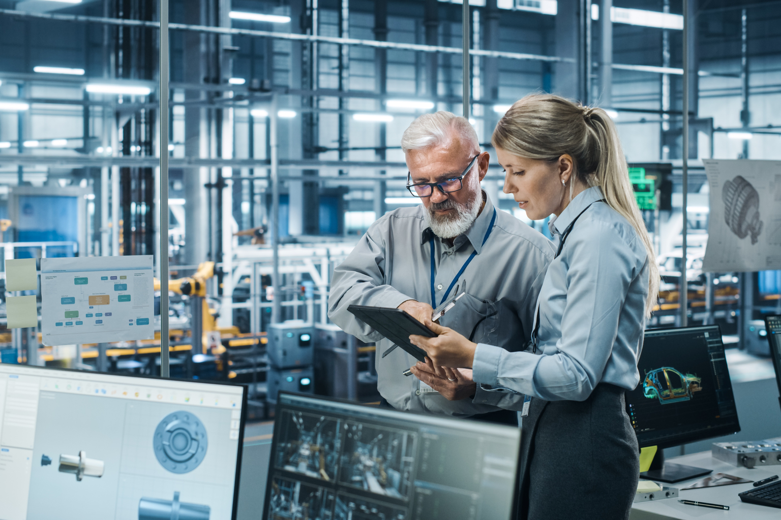 Car Factory Office: Manager Talks with Senior Engineer, Use Tablet Computer to Design Production Conveyor for Advanced Power Engines. Automated Robot Arm Assembly Line Manufacturing Vehicles