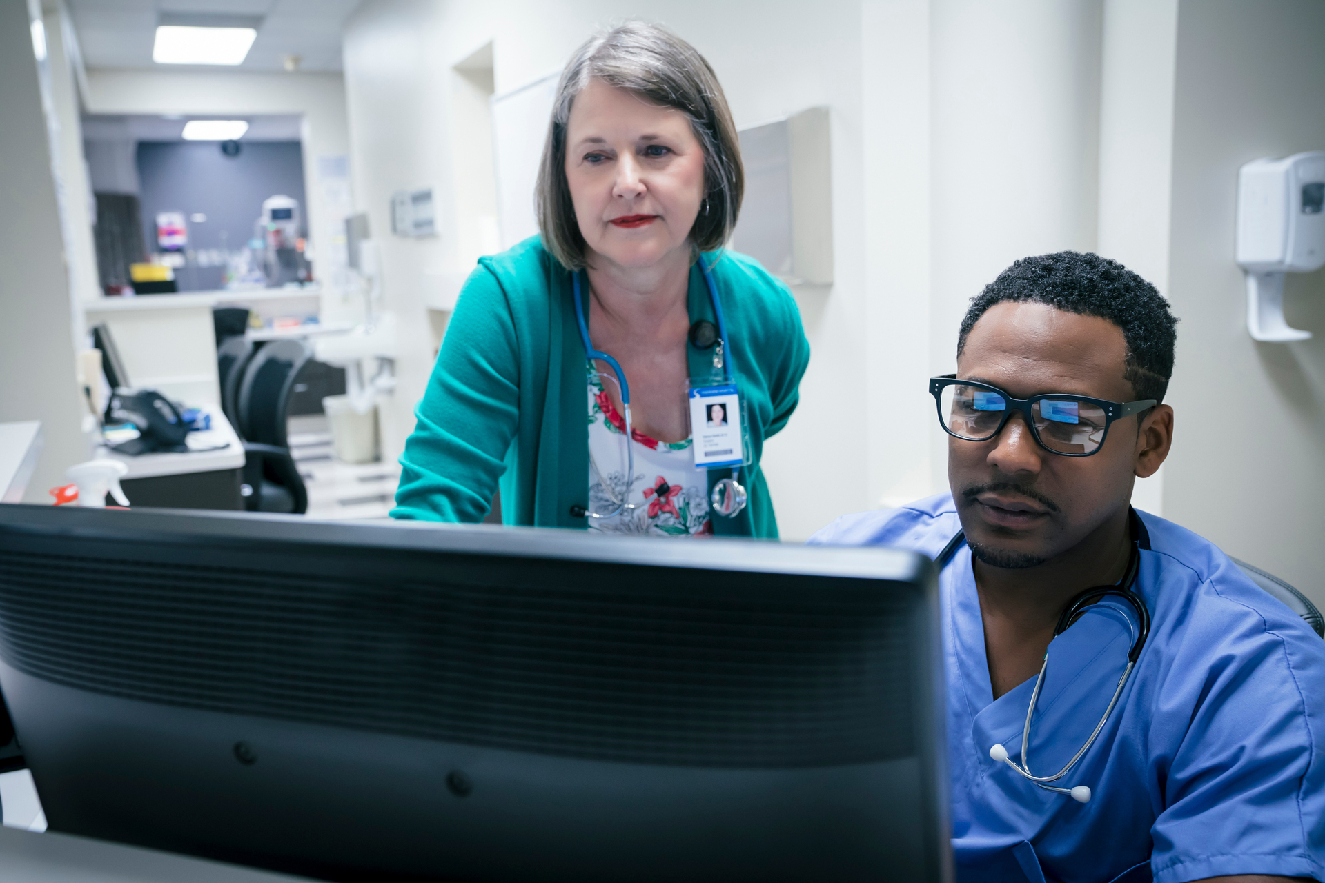 Nurse administrator and nurse review patient charts on nursing station computer