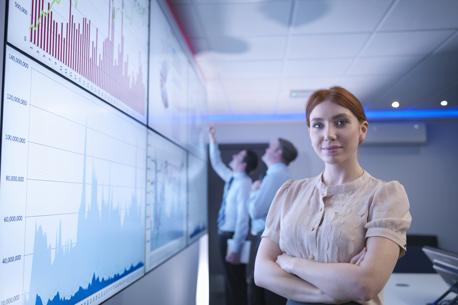 Businesswoman in front of graphs on screen in meeting room, portrait