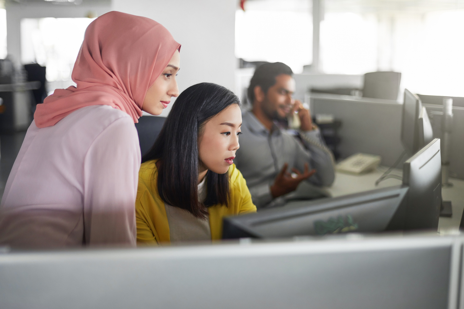  Female colleagues working at computer desk