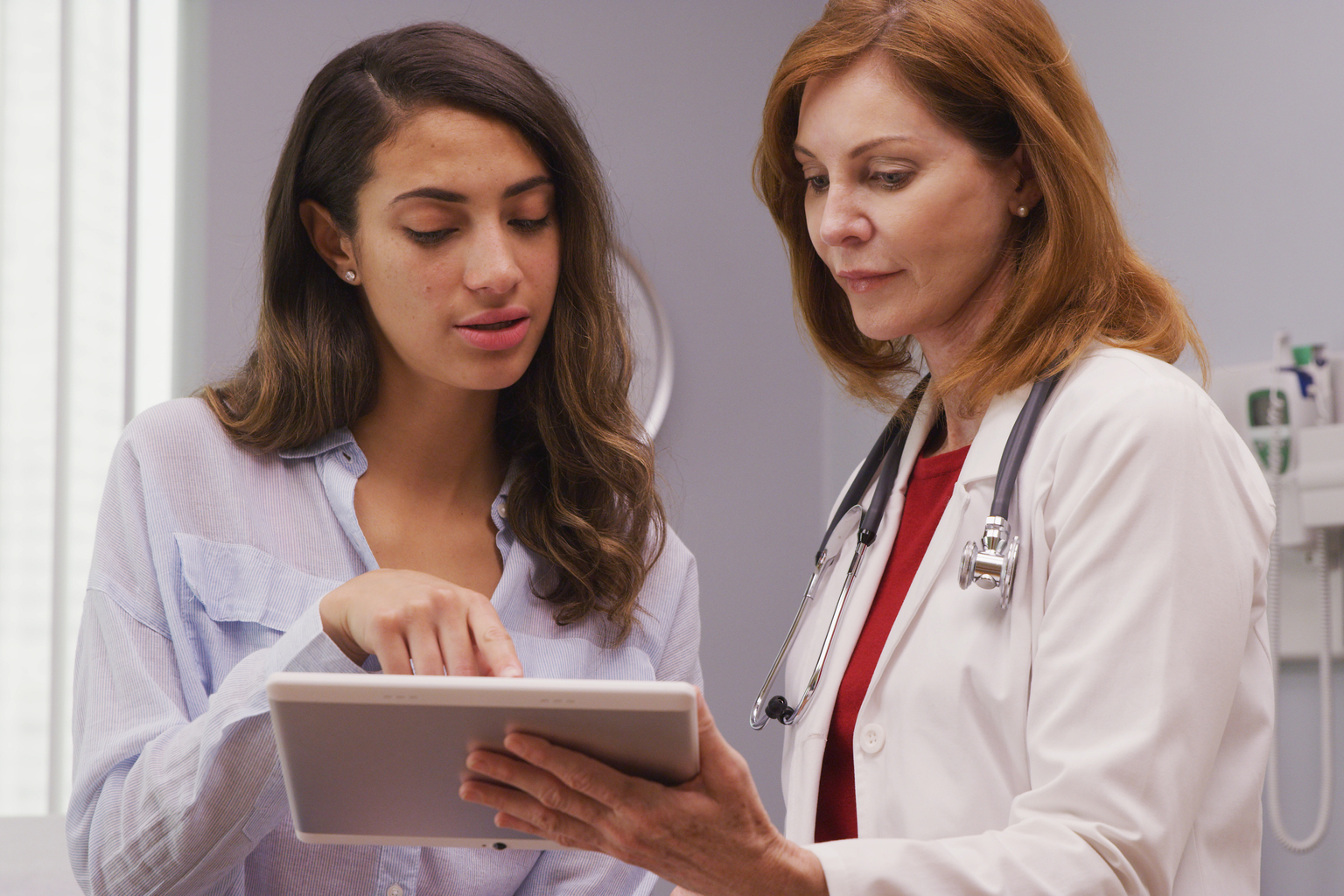 Female doctor looking at a tablet with female patient to review test results and discuss future of her health