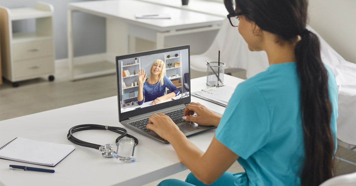 Healthcare worker sitting at desk on laptop with patient, telemedicine/telehealth