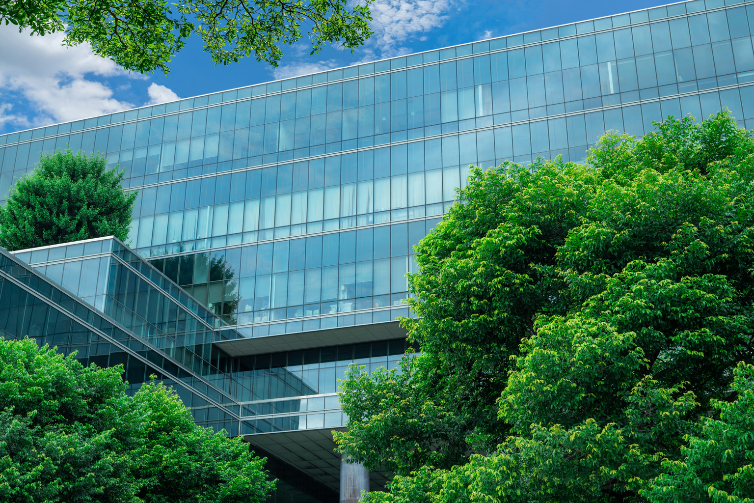 Eco-friendly building in the modern city. Sustainable glass office building with trees for reducing heat and carbon dioxide. Office building with green environment. Corporate building reduce CO2.