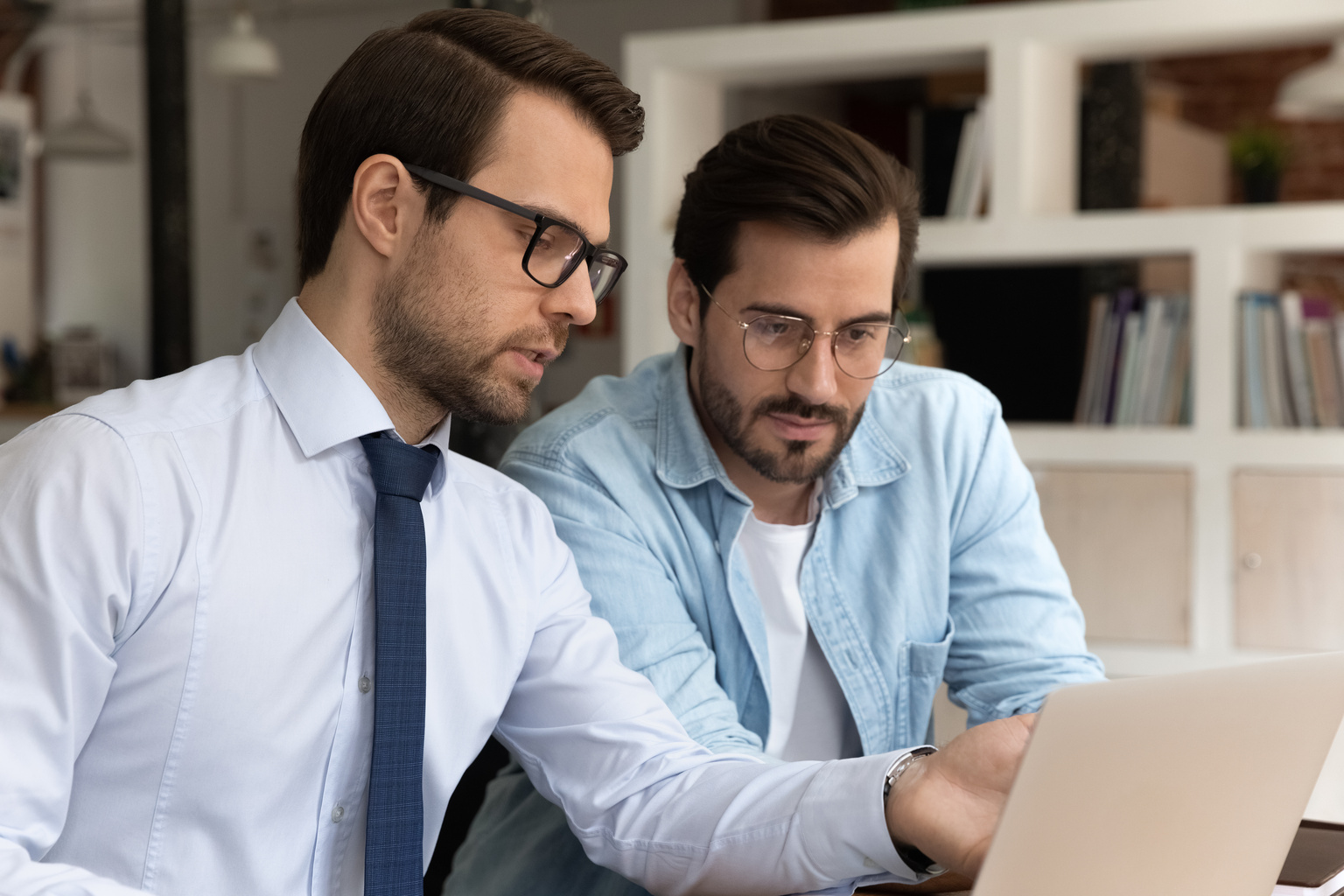 Close up confident mentor in glasses looking and pointing finger at laptop screen