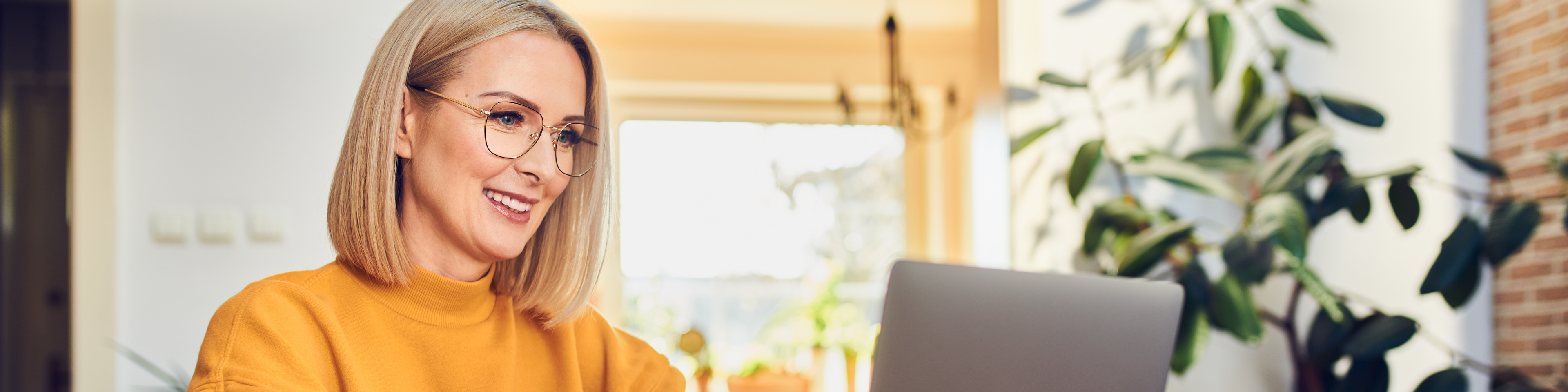 Portrait of middle aged woman sitting at dinning with laptop working at home