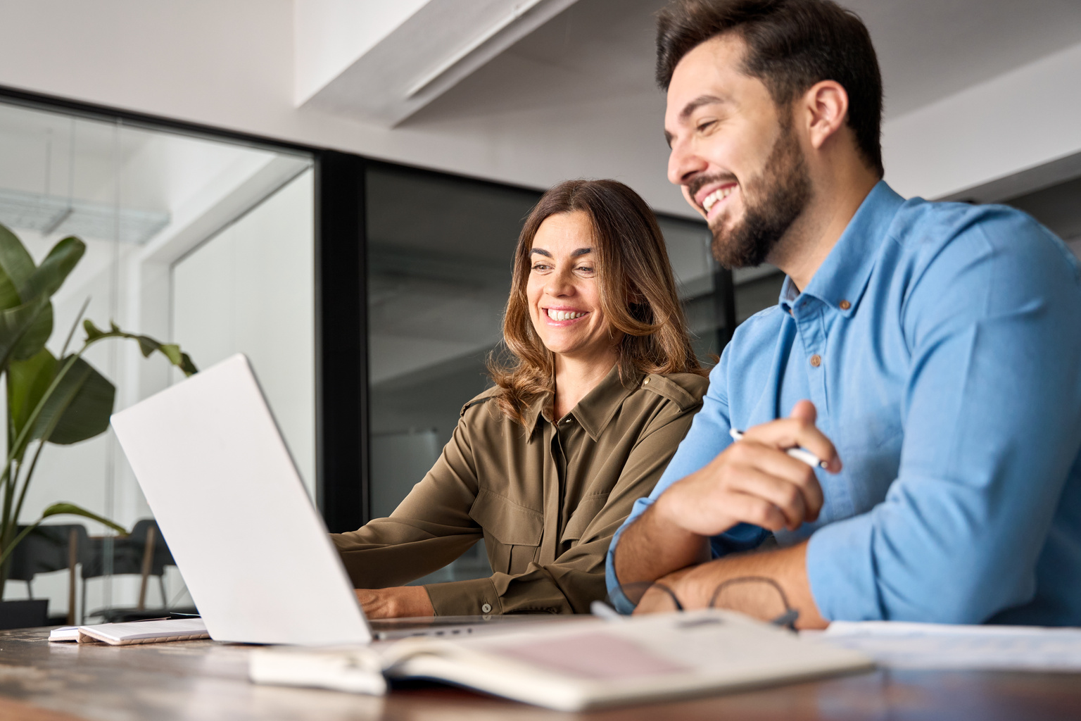 A woman and man working together at office desk laptop computer