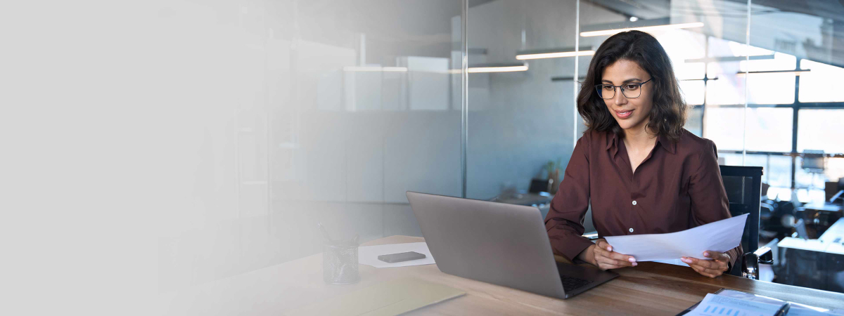 Focused latin hispanic business woman working on laptop computer reading financial document report in office