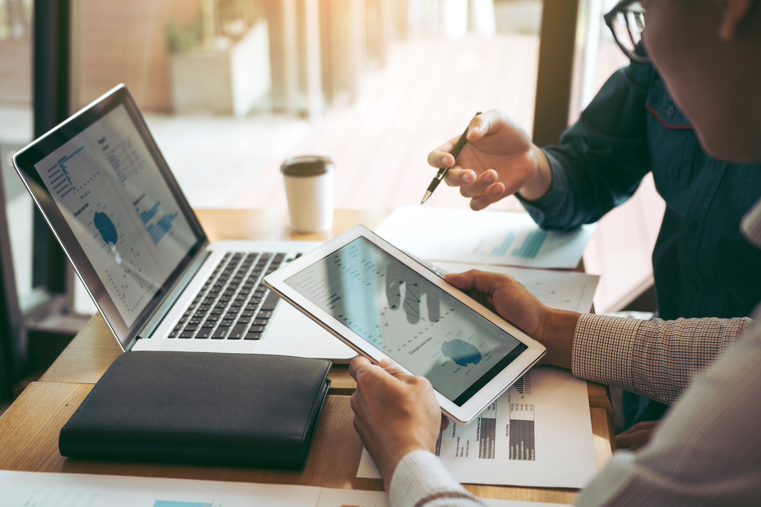 Business partnership coworkers using a tablet to chart company report in office room