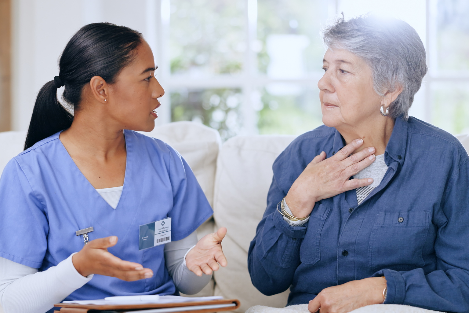 A nurse treats a senior patient on the couch in patient's home 