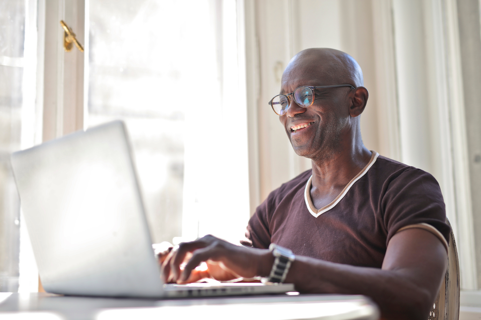 Portrait of middle aged male using a laptop on a table at home AS982934030