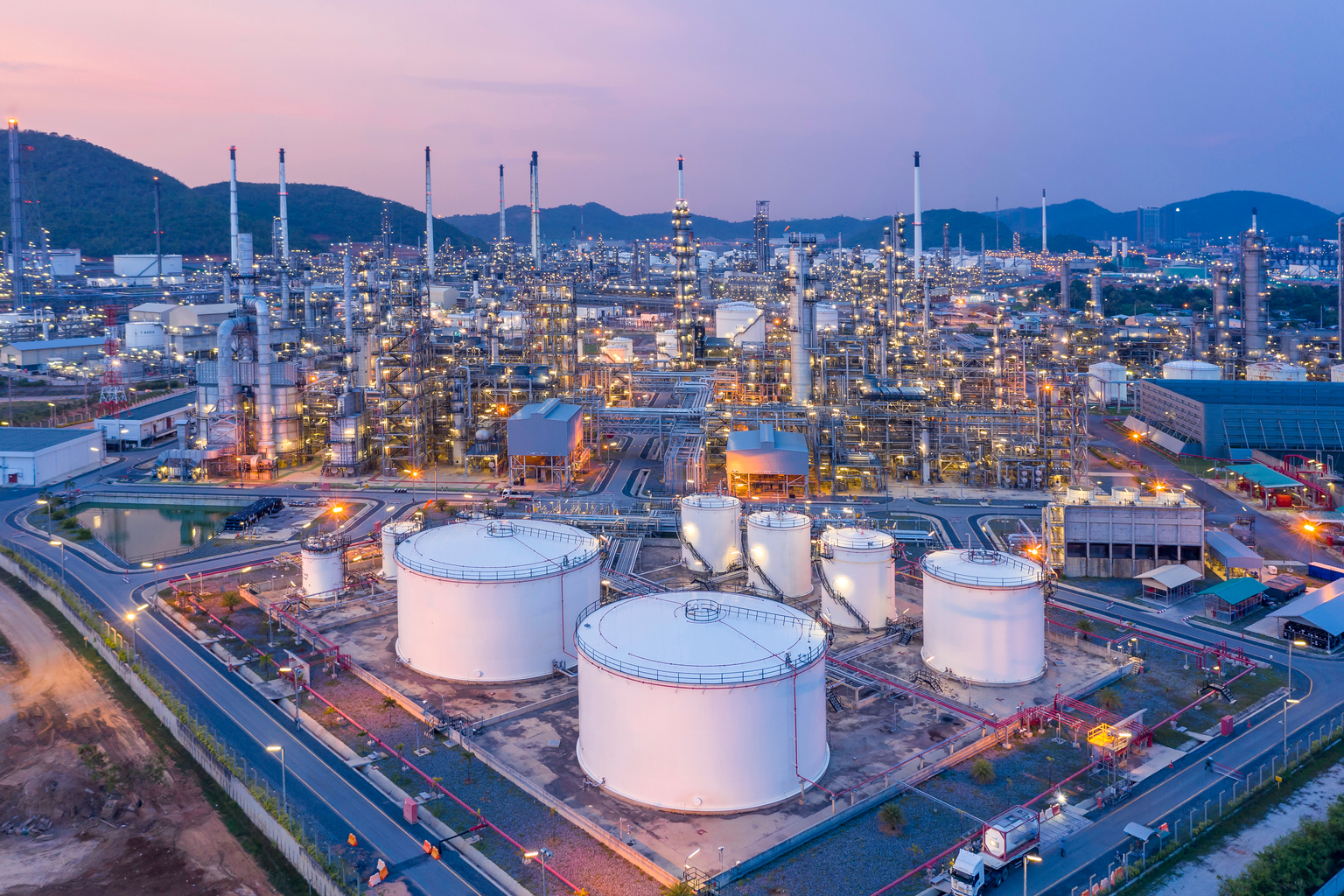 Aerial view Refinery and oil storage tanks at dusk and night. Petrochemical and energy oil industries.