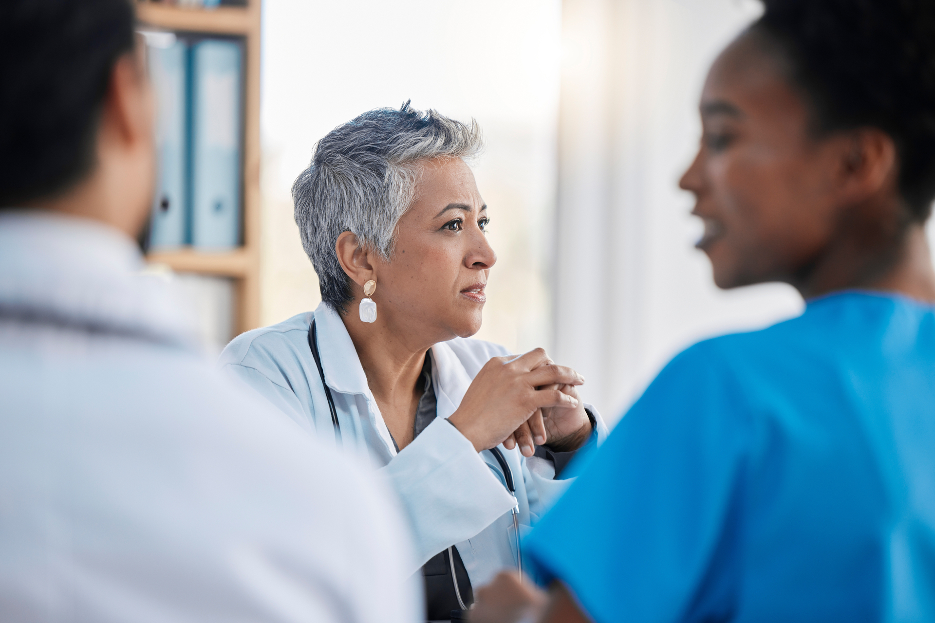 Senior medical professional leads meeting with colleagues