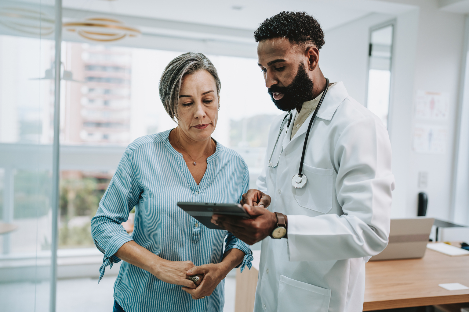 Male doctor talking to female patient holding digital tablet