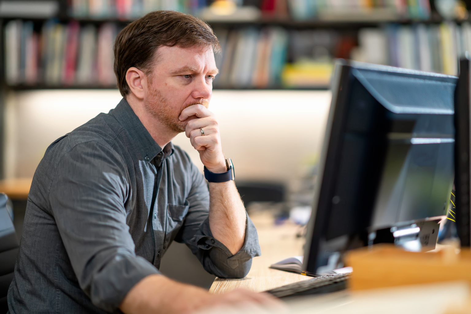 Portrait of a business professional man sitting at table, working with a desktop in the office