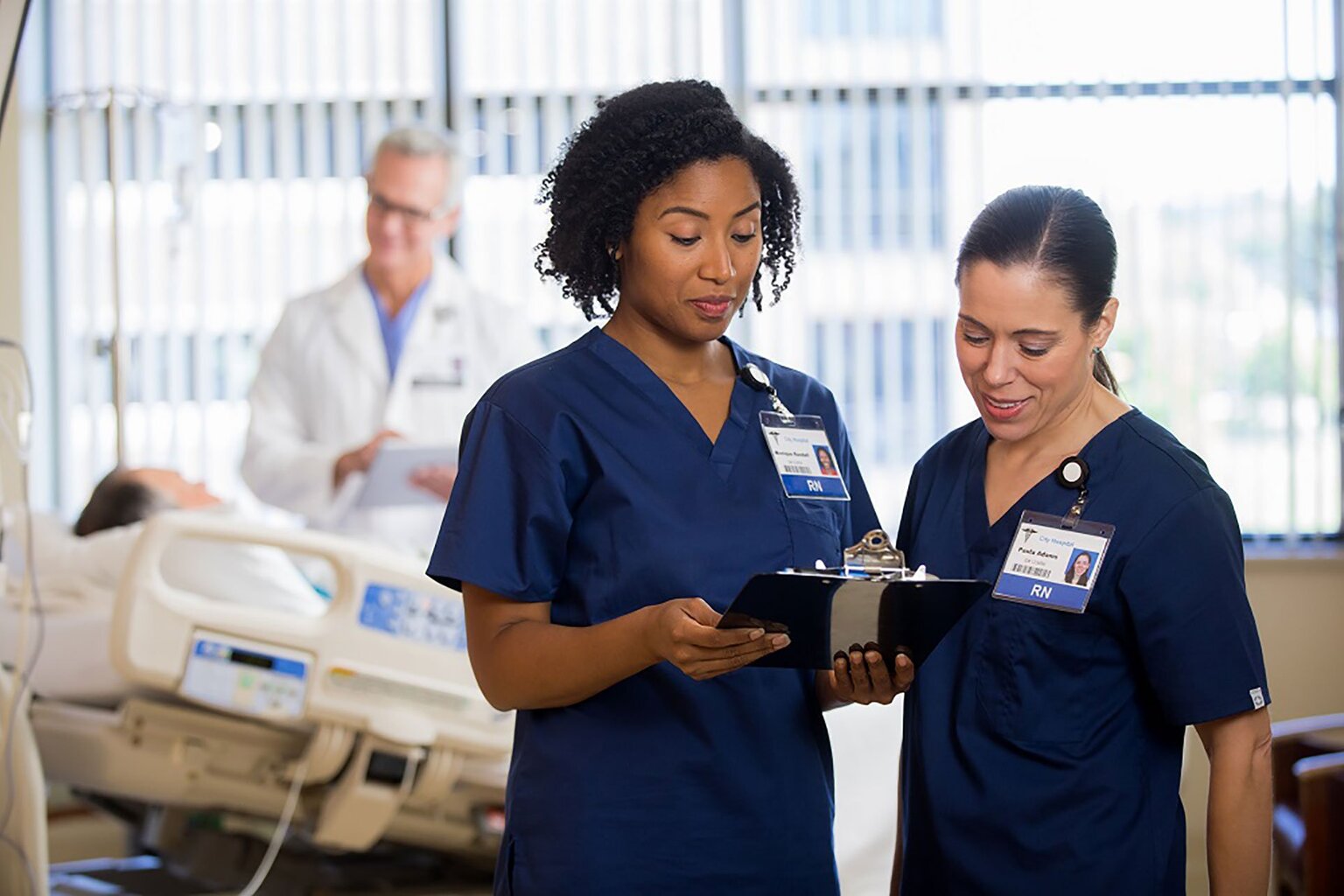 Two female nurses looking at a clipboard