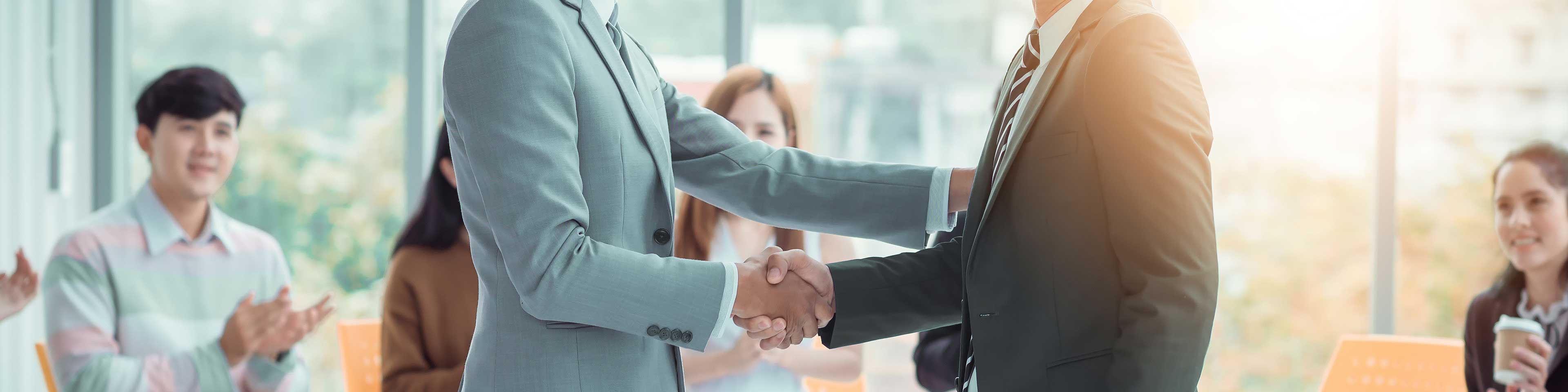 Men shaking hands and others clapping