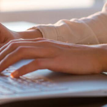 woman typing on a laptop; hands close-up