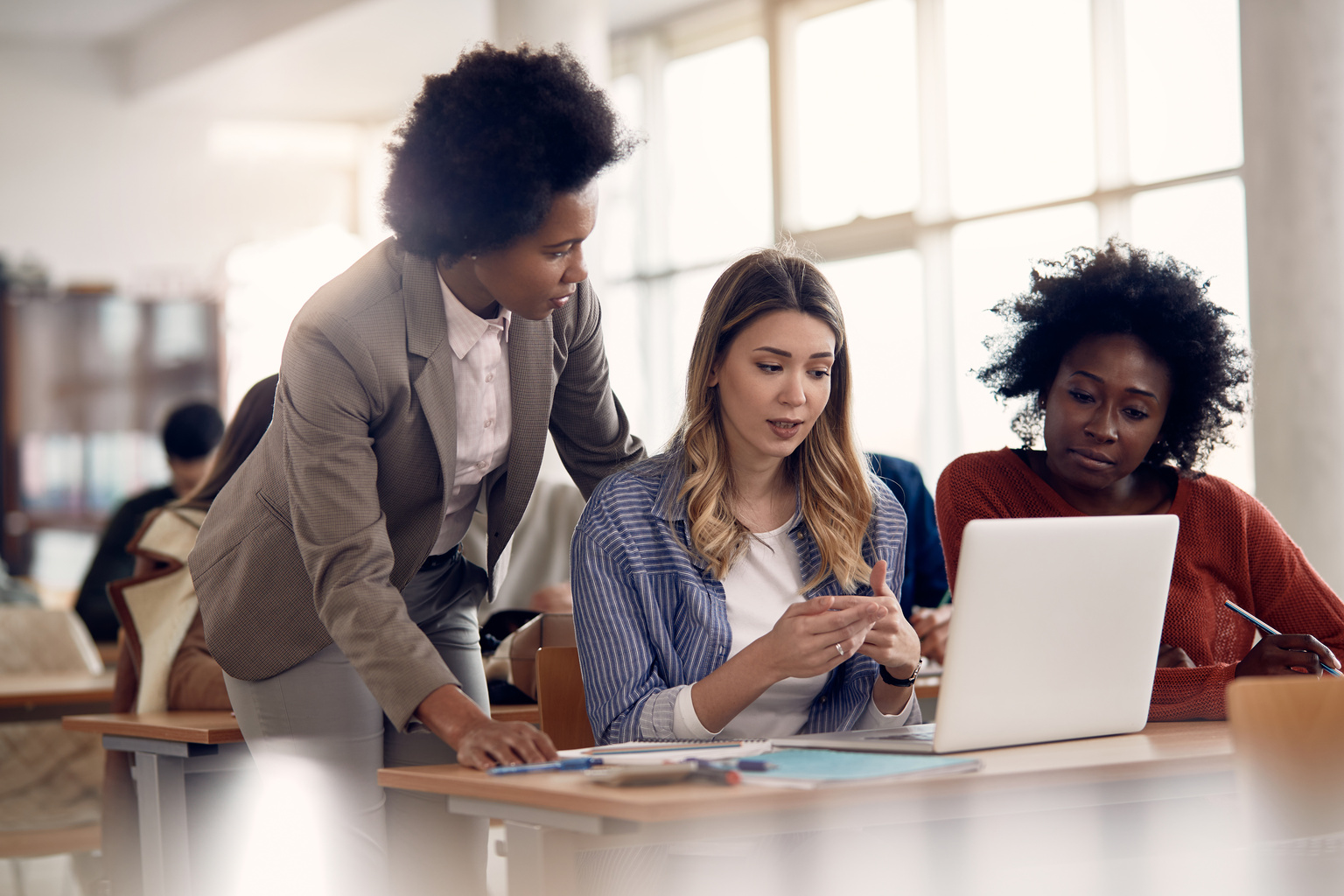 Two students engaged in class work with professor