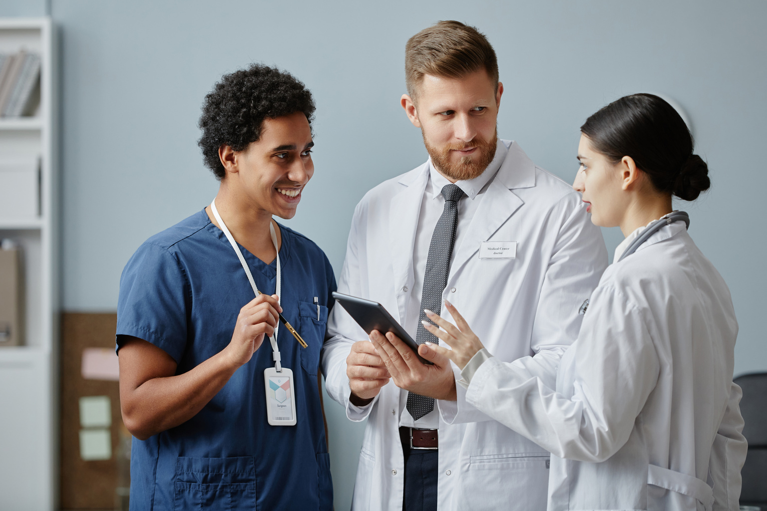 Waist up portrait of three doctors discussing patients case in clinic and holding tablet