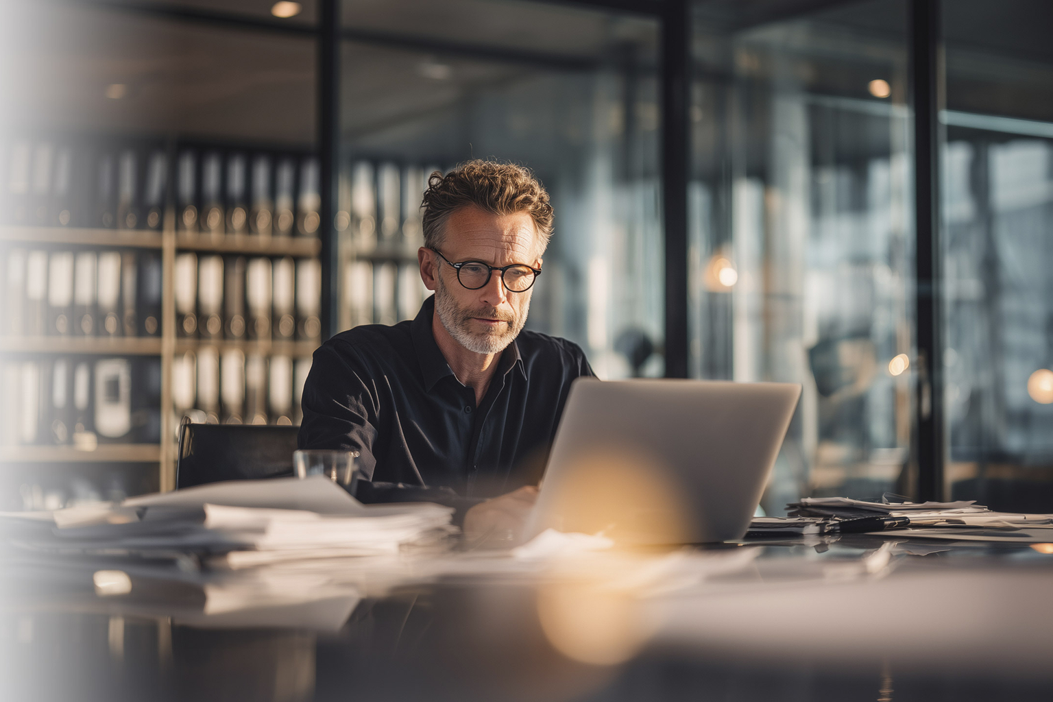 Old man with glasses sitting in fron of a laptop