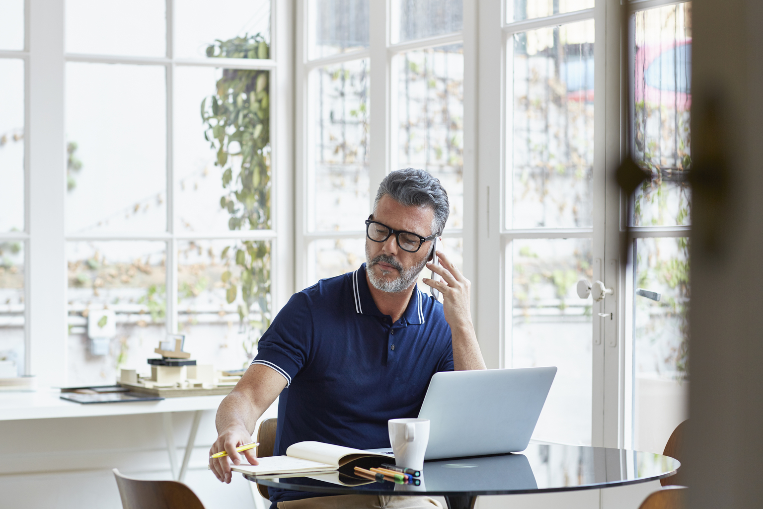 Businessman using mobile phone while writing notes