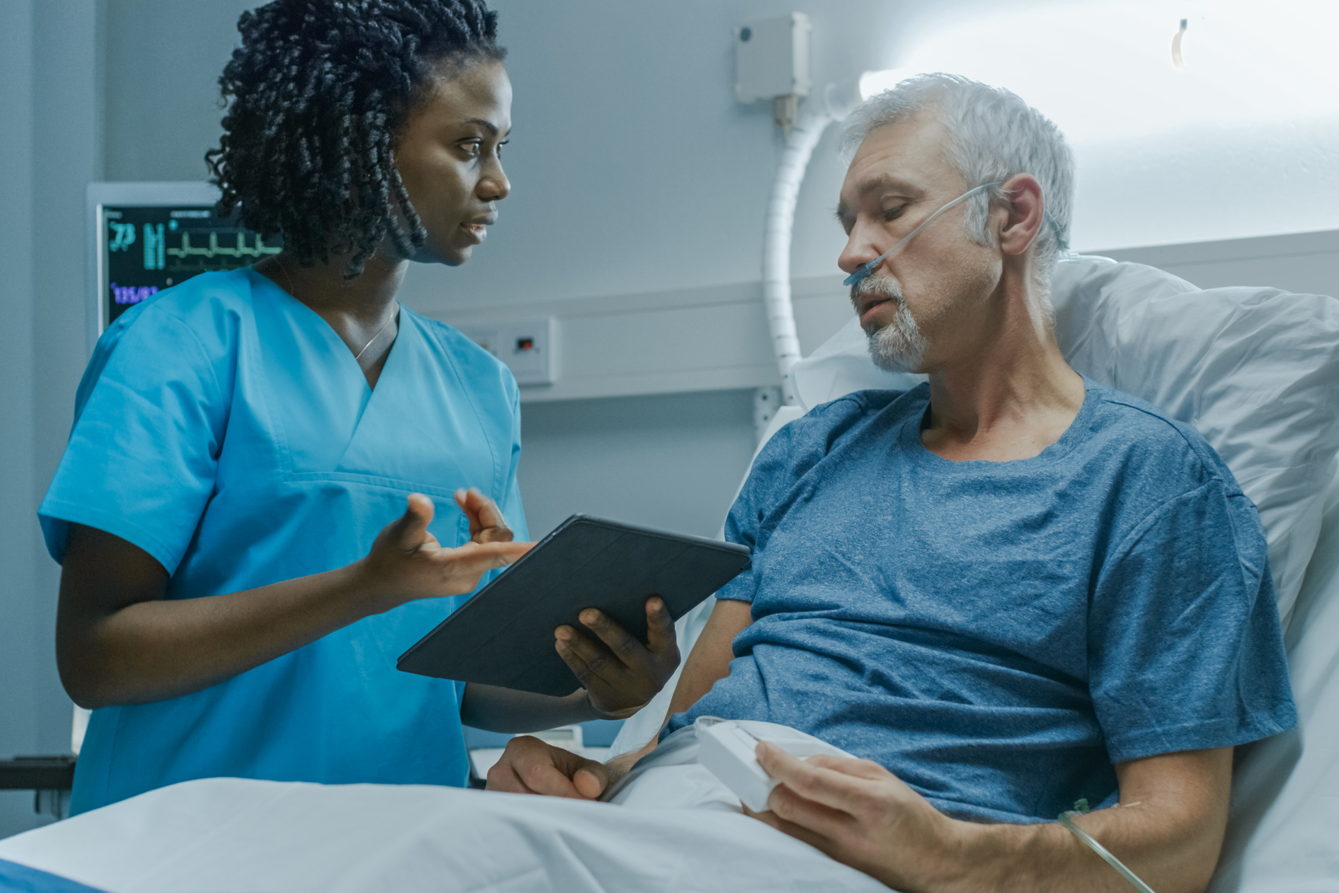 Patient Lying in the Bed Talking to a Nurse with Tablet