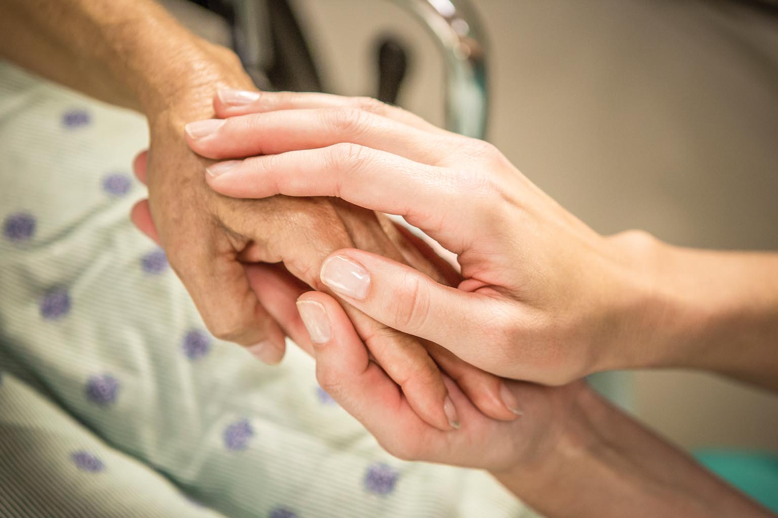 closeup of caregiver holding patient's hands