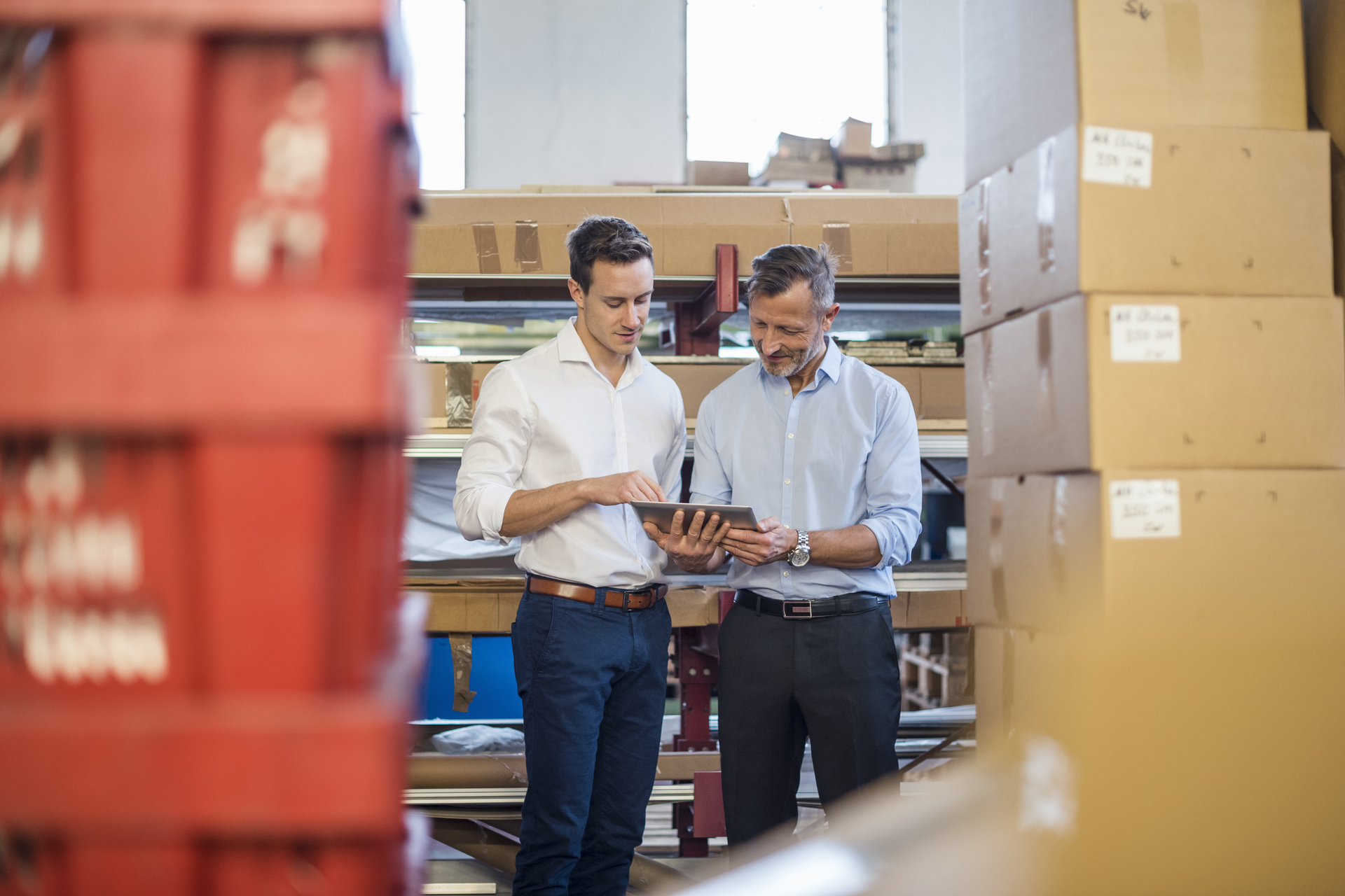 Business people discussing using a tablet at distribution warehouse