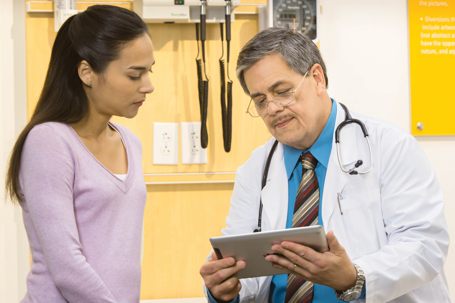 Male doctor and female patient looking at UpTodate on a tablet