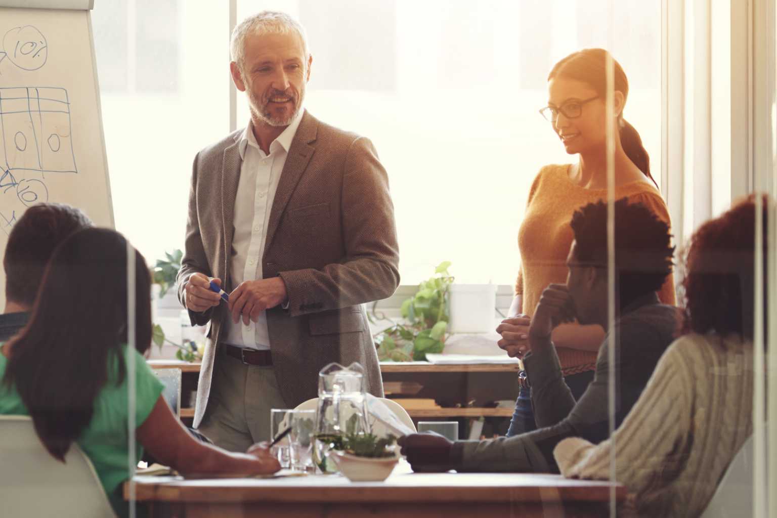 Team meets in conference room around flip chart