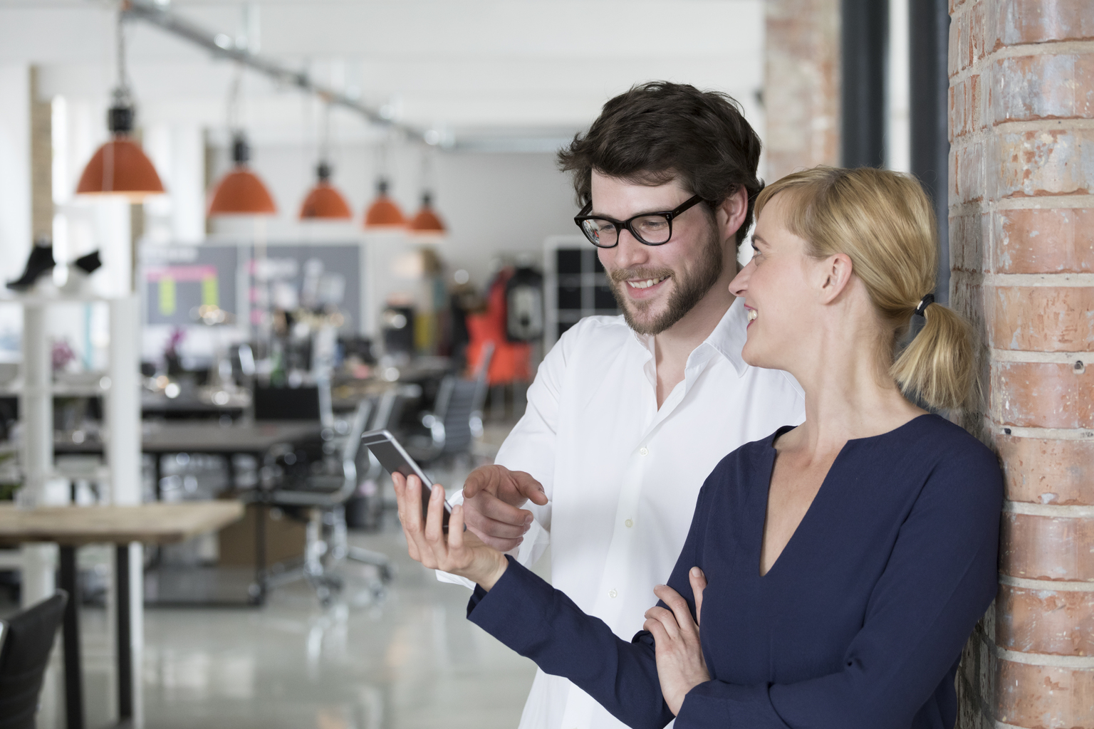 Young businesspeople in their new office looking at smartphone