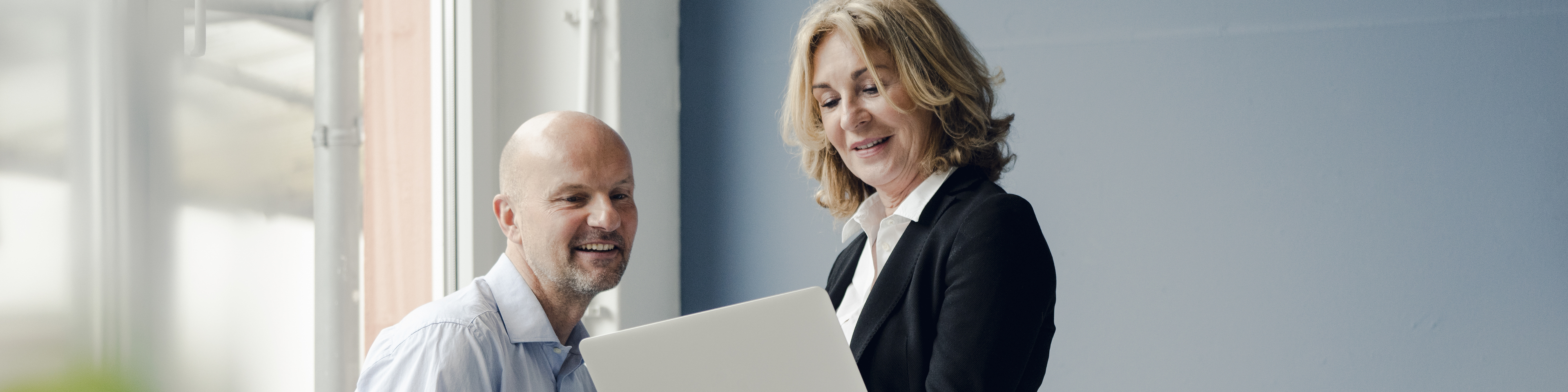 Woman in a Business suit discussing while holding her laptop