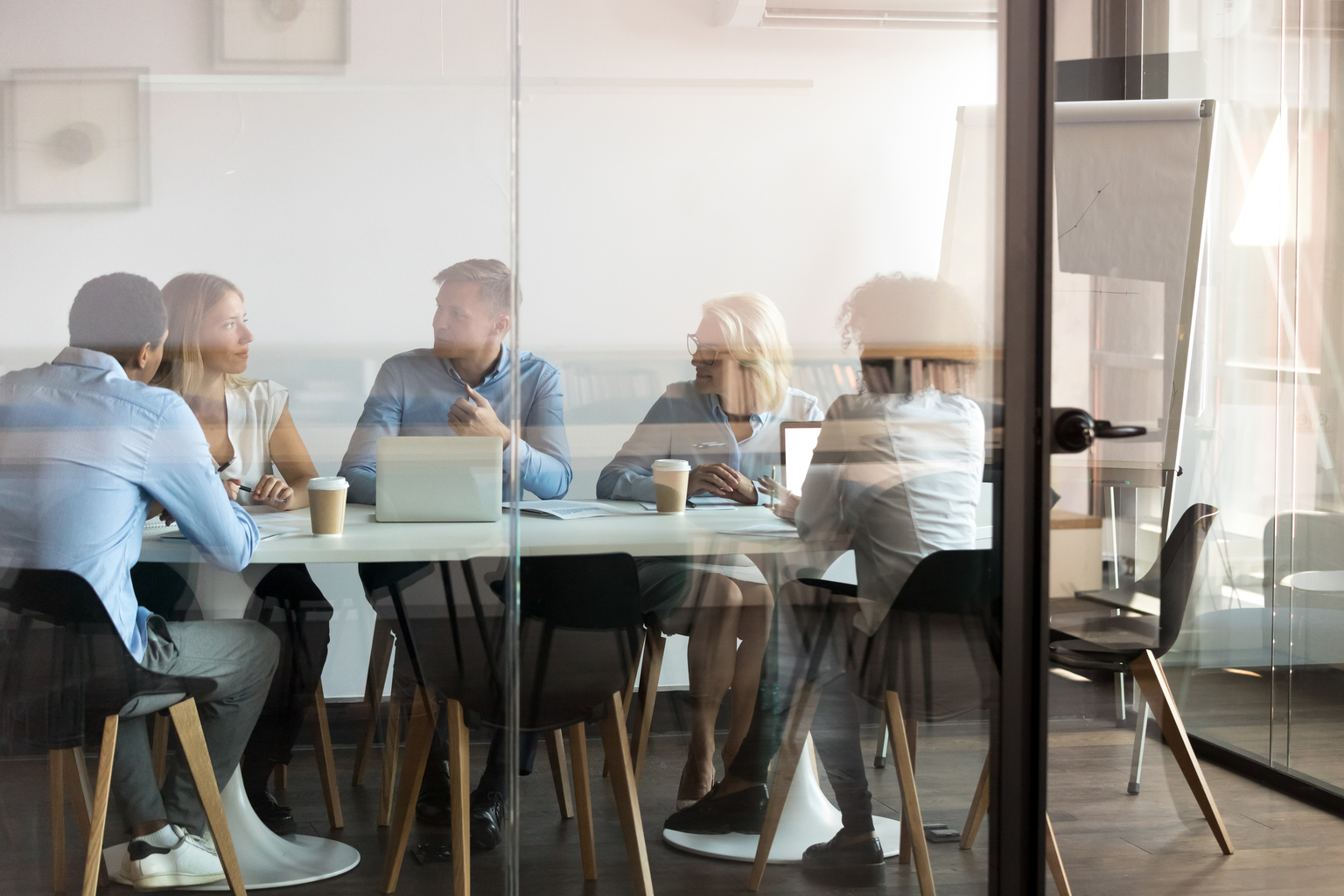 Professionals brainstorming BOI reporting strategies at modern office boardroom behind closed doors