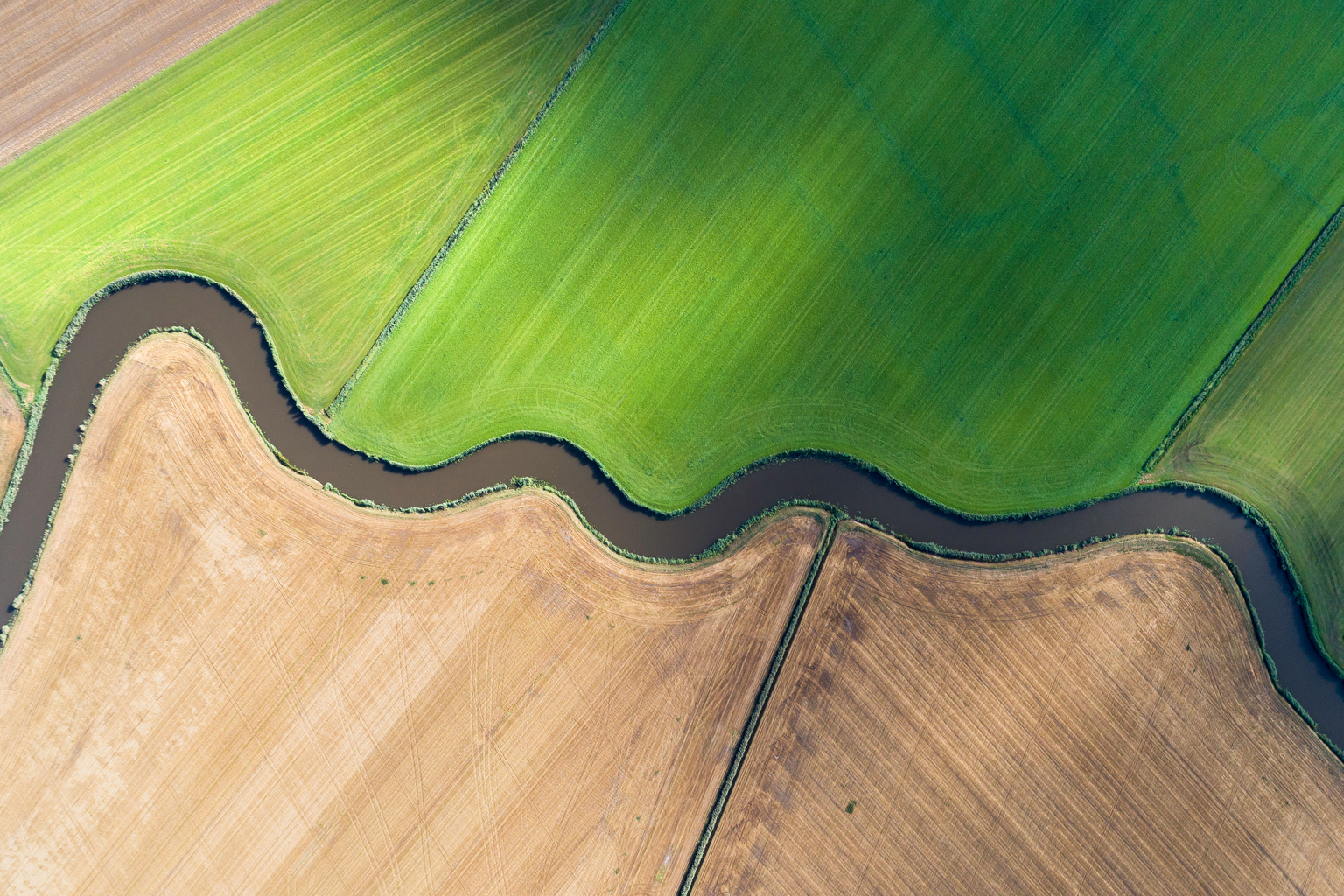 Aerial view of river bending through cultivated fields