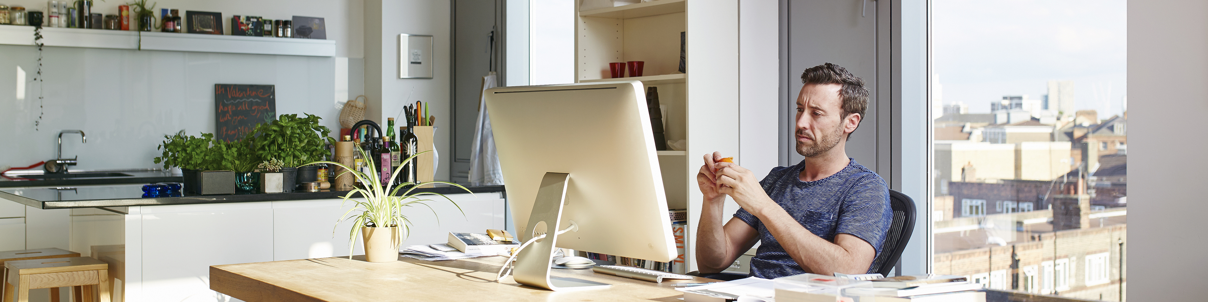 Man using desktop on his dining table next to the kitchen