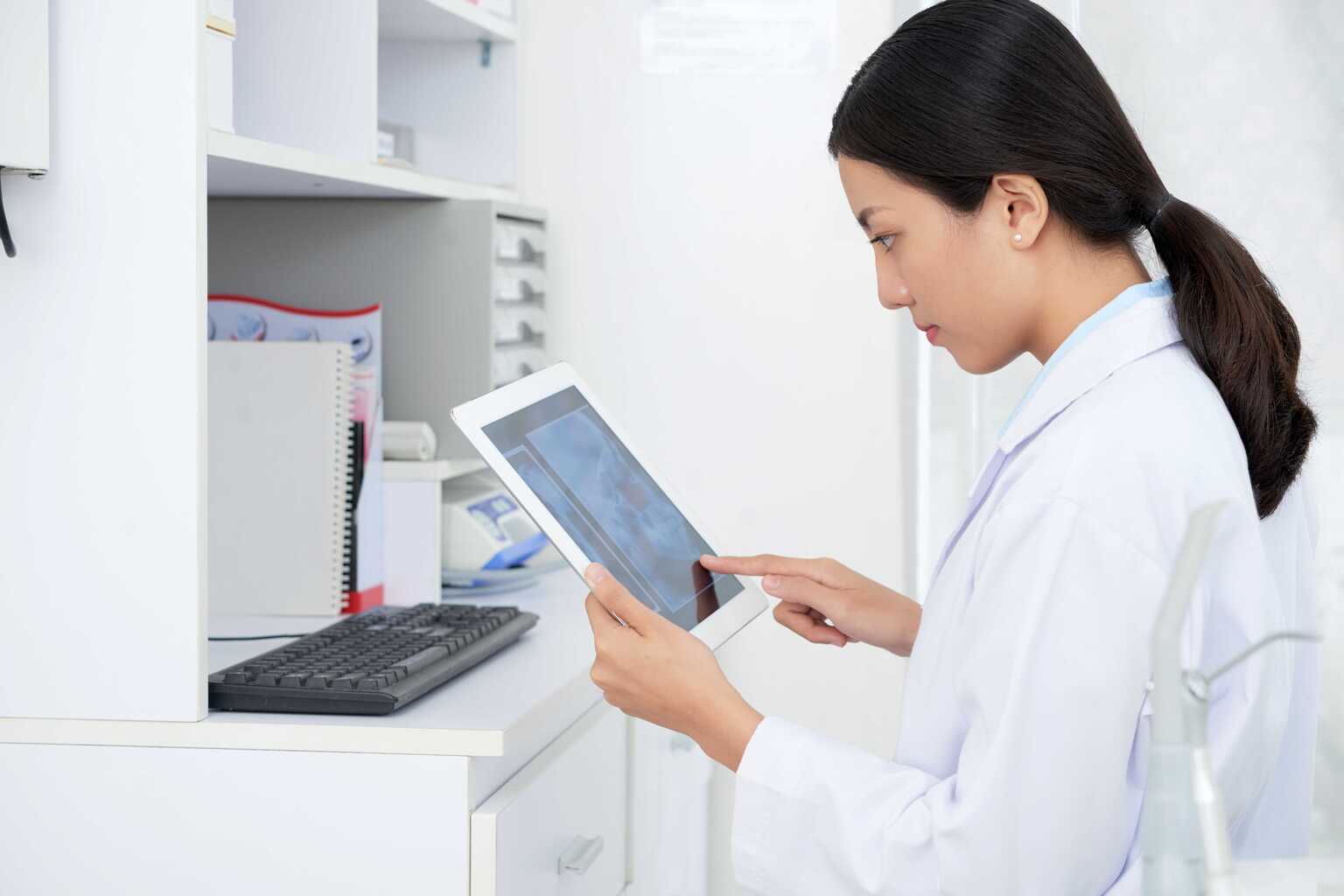 Female doctor sitting at desk holding tablet