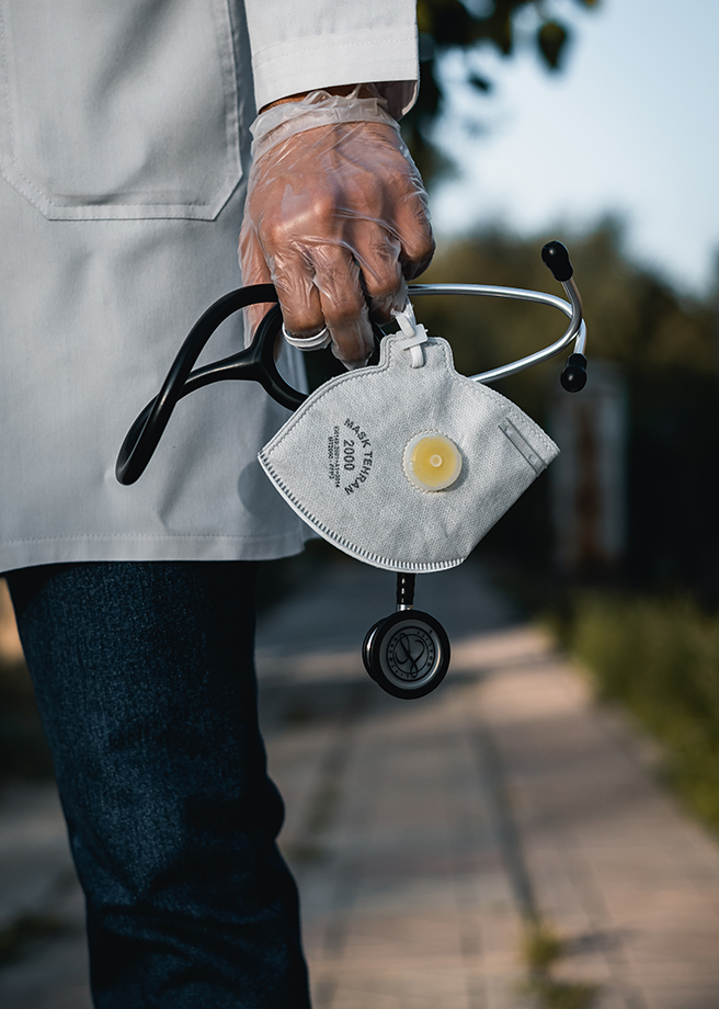 Close up on gloved doctor's hand holding mask and stethoscope