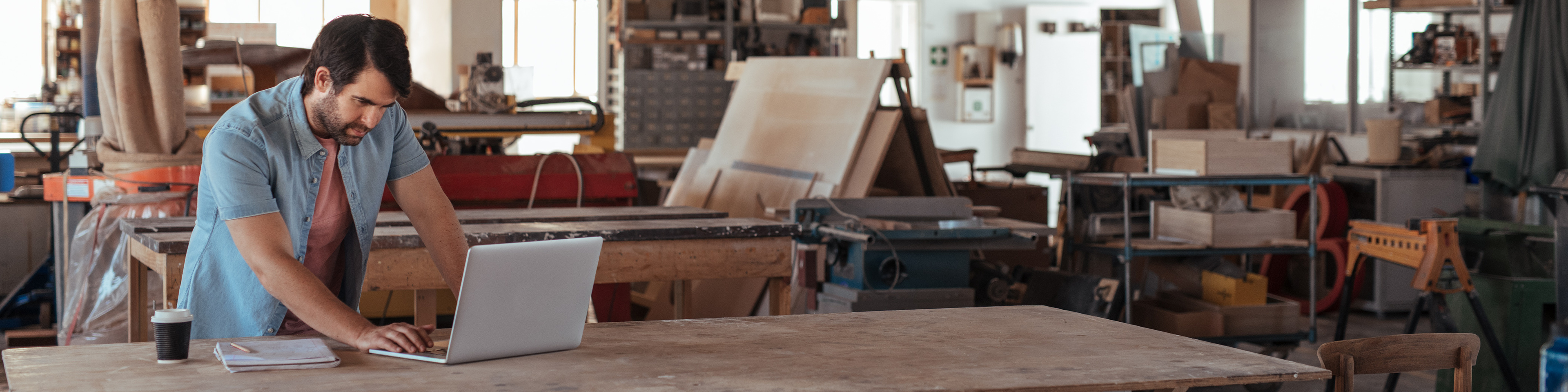 Young woodworker working online at a bench in his workshop